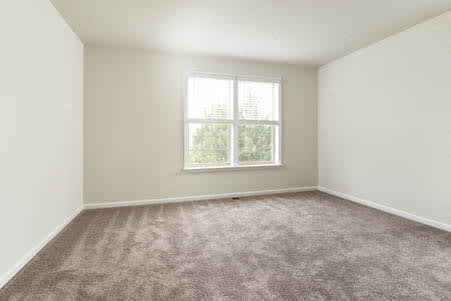 an empty room with a window and a carpet