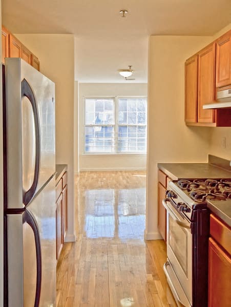 kitchen with hardwood floors and stainless steel appliances and wooden cabinets