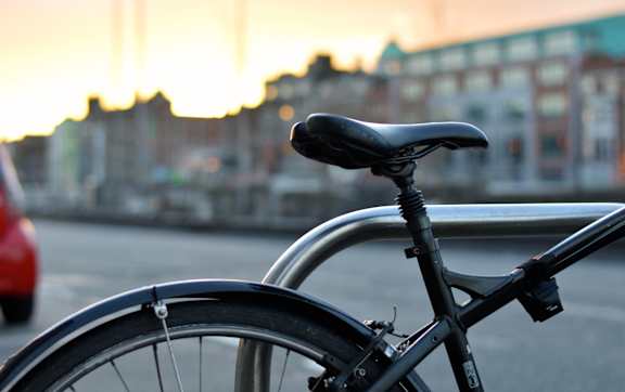 A bicycle is parked on the street with a sunset in the background.