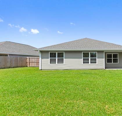 the backyard of a home with green grass and a blue sky