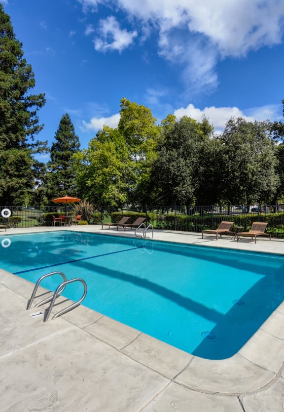 a swimming pool with trees in the background and a blue sky at Vineyard Terrace Apartments, Napa, CA