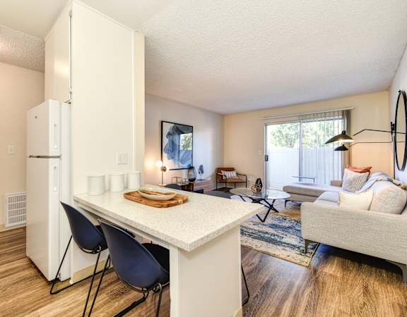 a kitchen with a white refrigerator freezer next to a living room with a couch and a coffee at Renaissance Park Apartments, California, 95618