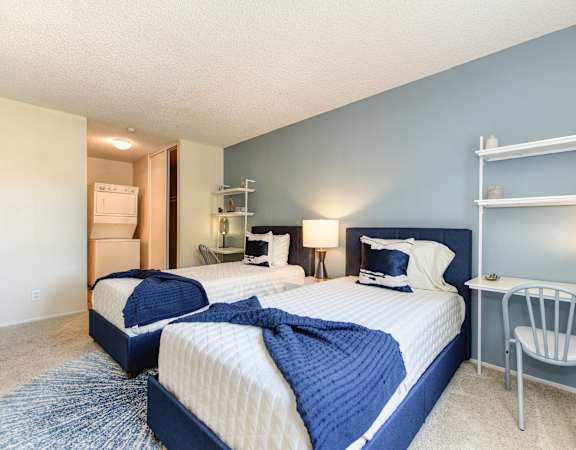 a bedroom with two beds and a desk with a chair at Renaissance Park Apartments, California, 95618