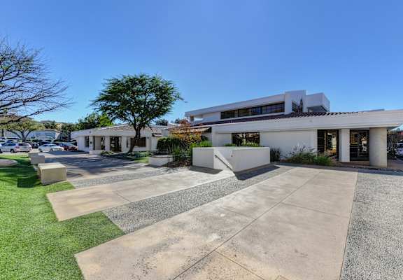 A modern building with a white facade and a parking lot in front.