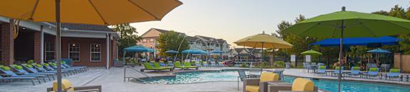 a swimming pool with chairs and umbrellas at the resort at The Madison Apartment Homes in TX 75703