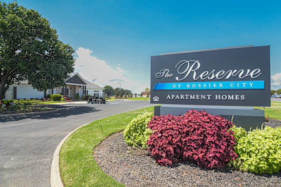 a swimming pool with chaise lounge chairs and a pool house in the background at Reserve Of Bossier City Apartment Homes in Bossier City, LA 71111