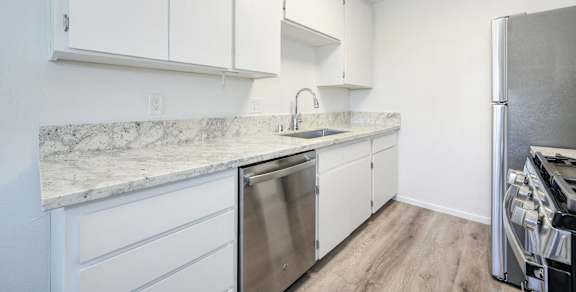 A kitchen with white cabinets and a marble countertop.