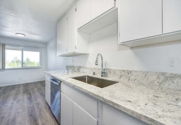 A kitchen with a marble countertop and white cabinets.