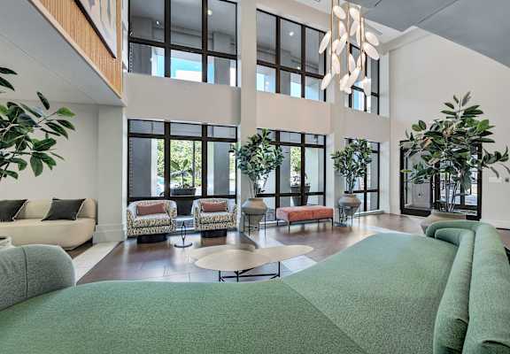 A large, modern living room with a green carpet and a chandelier.