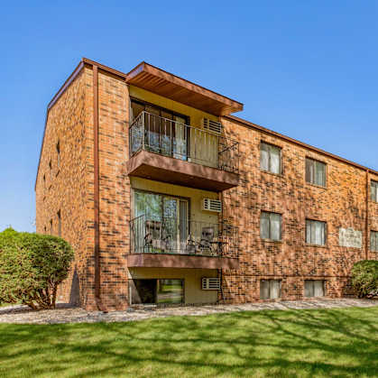 a brick apartment building with green grass and a blue sky