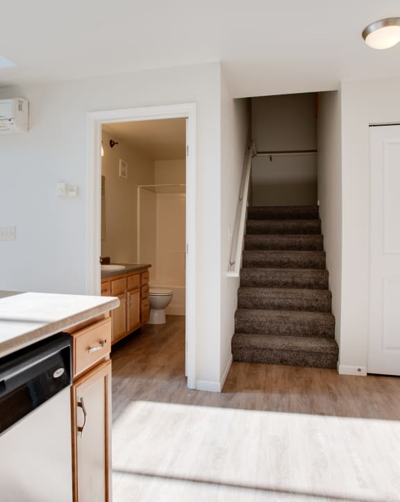 an empty living room with a kitchen in the background