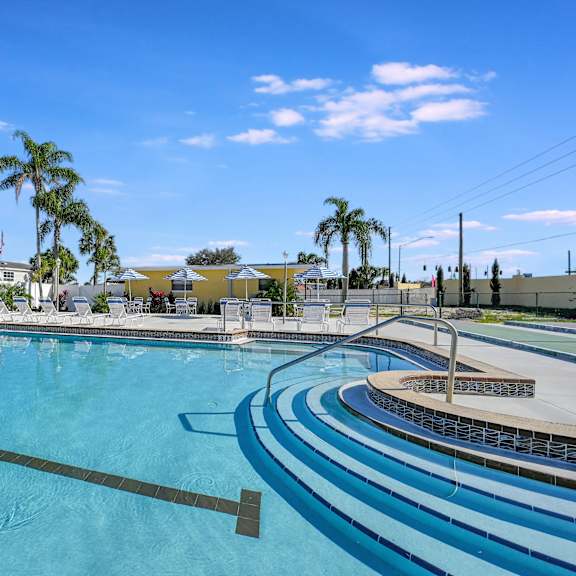 a swimming pool with palm trees and buildings in the background