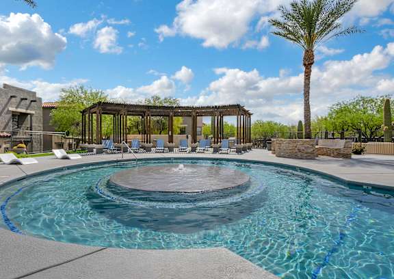 A pool with loungers and a building in the background.