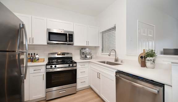 A kitchen with white cabinets and a black countertop.