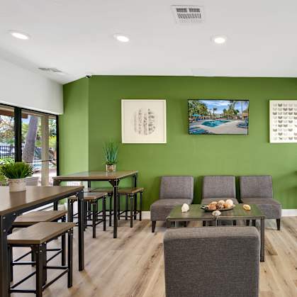A room with green walls and wooden floors has a long table with chairs on both sides.