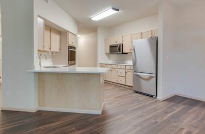 A kitchen with wooden floors and a white refrigerator. at Eighth Street Manor  Apartments, Fargo, ND