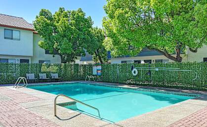 A swimming pool surrounded by a fence and trees.