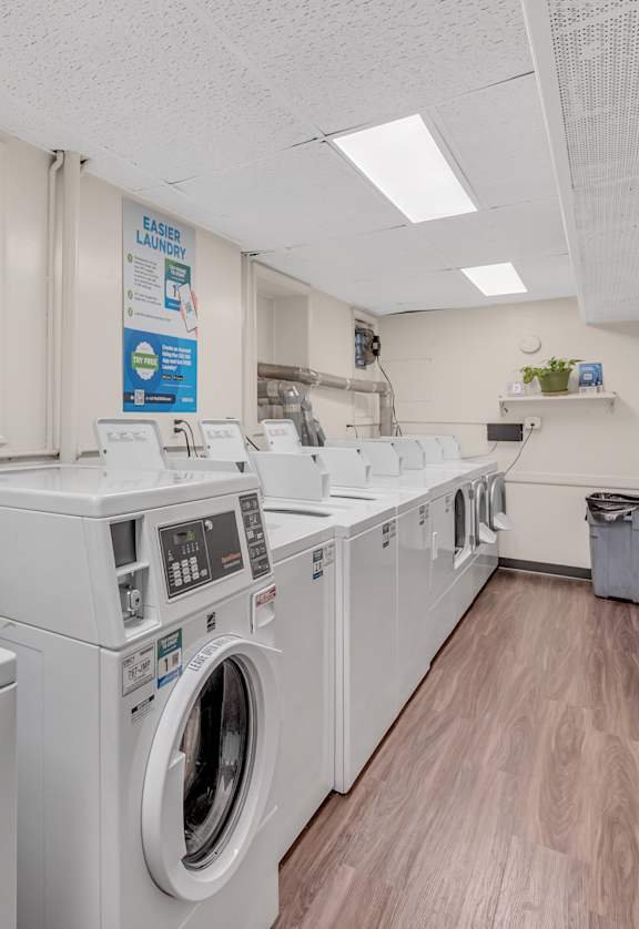 a laundromat with four washers and four dryers in a room with