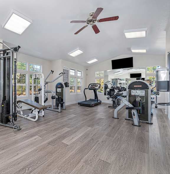 a gym with weights machines and a TV at Hidden Oaks Apartments, Citrus Heights, California