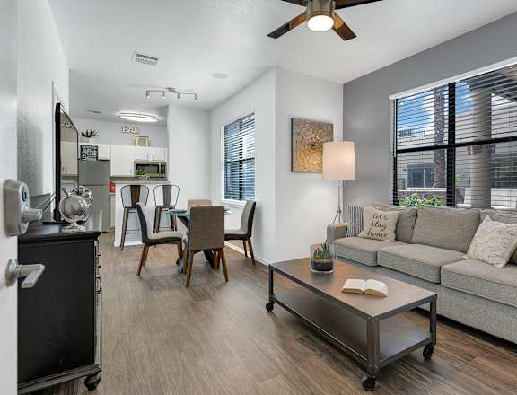 A living room with a grey couch, a coffee table, and a ceiling fan.