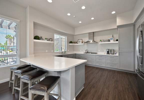 A modern kitchen with a white island and bar stools.