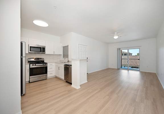 A spacious kitchen with white cabinets and a wooden floor.