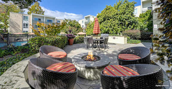 A patio with a fire pit and chairs.