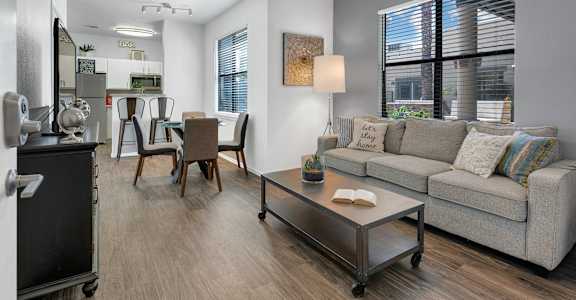 A living room with a grey couch, a coffee table, and a ceiling fan.