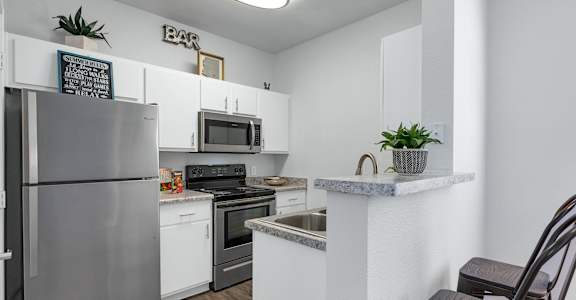 A kitchen with a refrigerator, stove, and microwave.