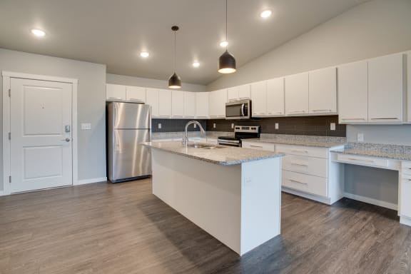 a kitchen with white cabinets and a white island with granite countertops