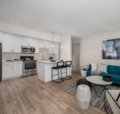 a living room with a couch a table and a chair and a kitchen with a stove at Pinecrest Apartments, Davis ,95616