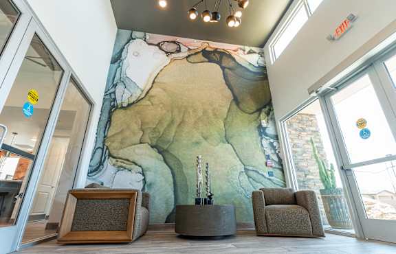 A room with a large mural of a landscape, a chair, and a small table.