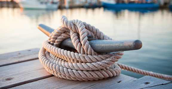 a rope laying on a dock by the water at The Port at East Beach Apartments and Marina, Virginia