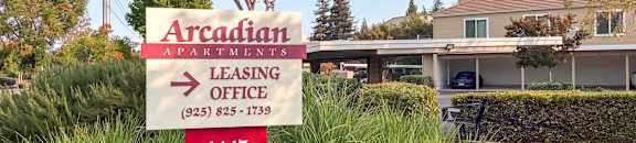 A sign for Arcadian Apartments leasing office with a phone number.