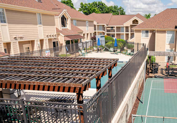 a fenced in tennis court with apartments in the background