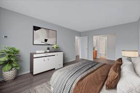 A bedroom with a bed, nightstand, and a plant.