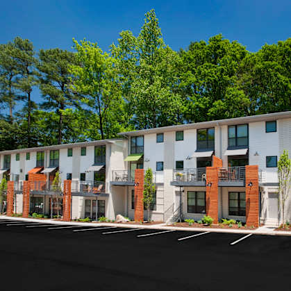 A row of modern townhouses with balconies and trees in the background.