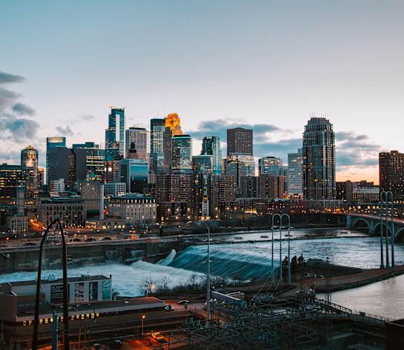 A city skyline at dusk with a river running through it.