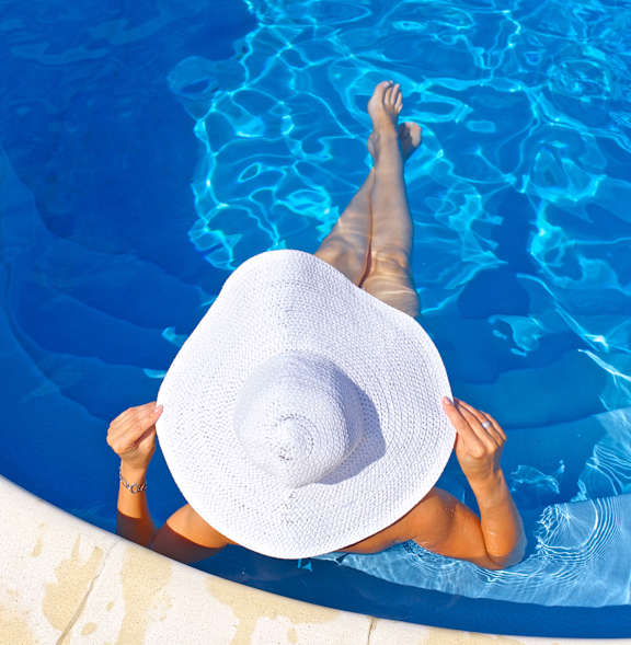 A woman in a white hat is floating in a pool at Montage at Hawk Ridge Apartments, Lake St. Louis