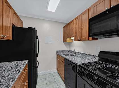 A kitchen with black appliances and wooden cabinets.