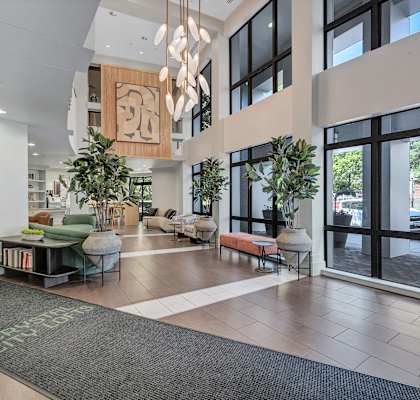 A modern lobby with a green rug on the floor and a large glass door.