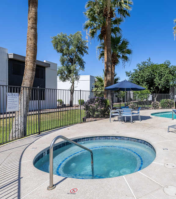 A pool surrounded by palm trees and lounge chairs.