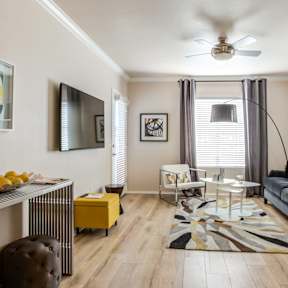 A living room with a black couch, a yellow ottoman, and a coffee table.