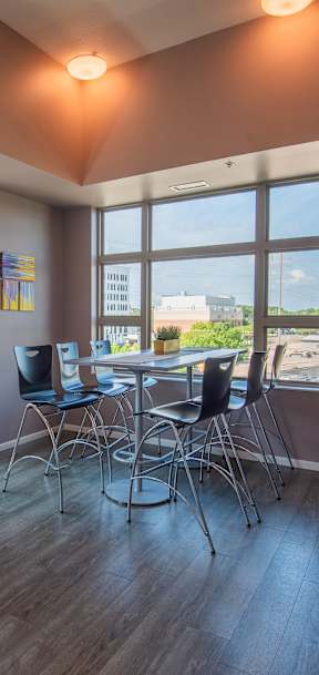 A room with a table, chairs and a couch with a painting on the wall.