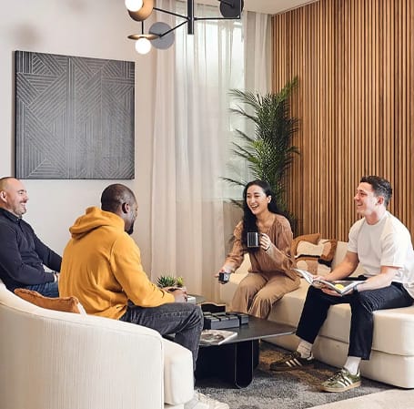 Four people are sitting on a couch in a living room.