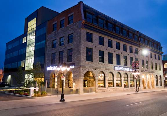 A modern building with a sign that says "milestones" is lit up at night.