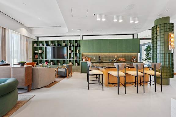 A modern kitchen with green cabinets and a dining table set for four.