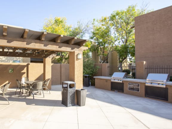 a patio with a barbecue grill and a table and chairs