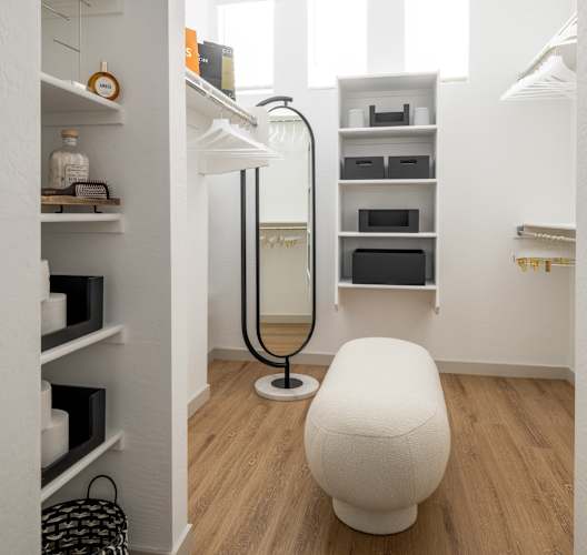 A white chair sits in a room with white walls and wood floors.