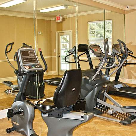 A gym with a treadmill, exercise bike and elliptical trainer.